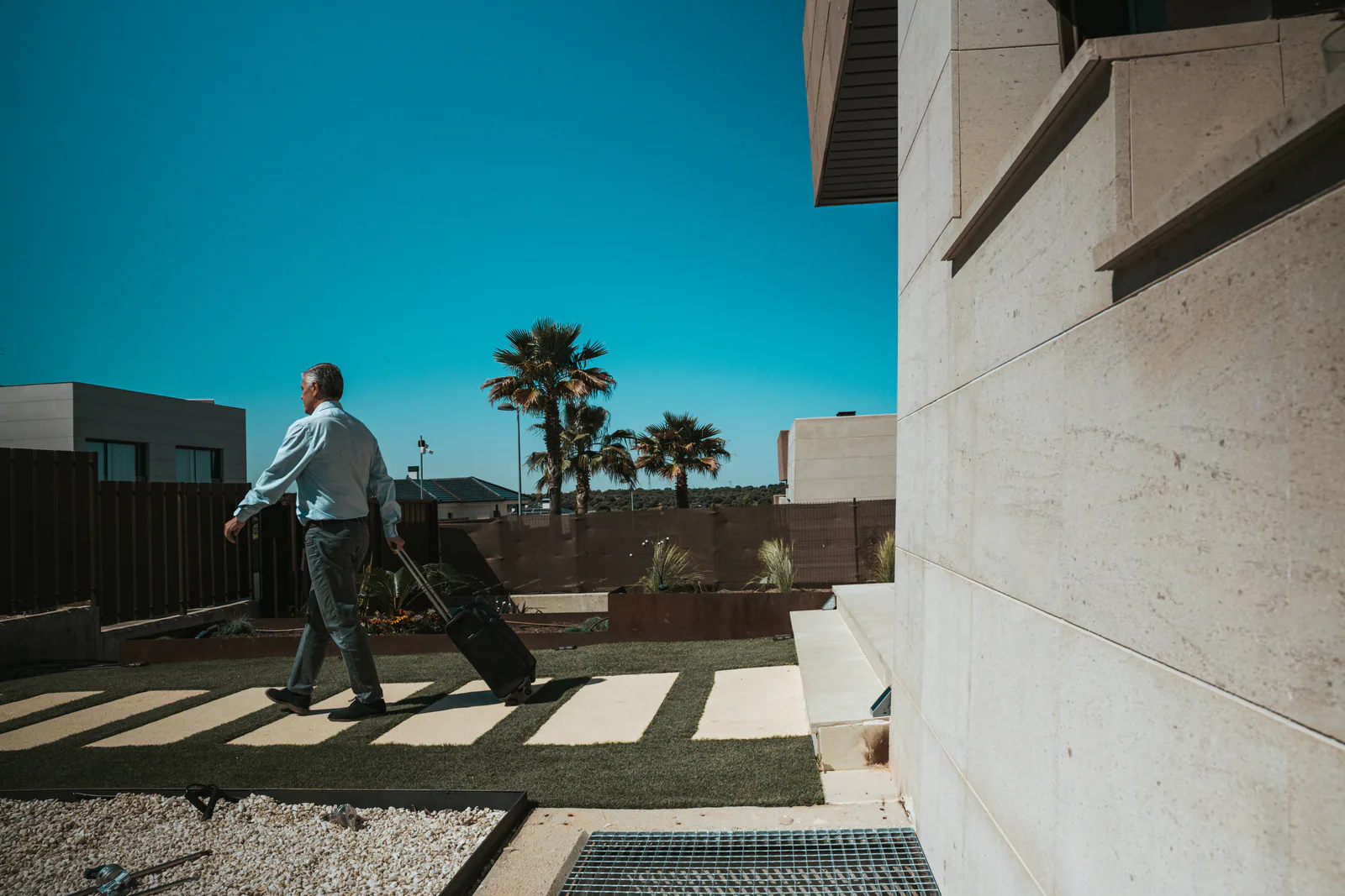 Person walking beside a contemporary home and Mediterranean garden